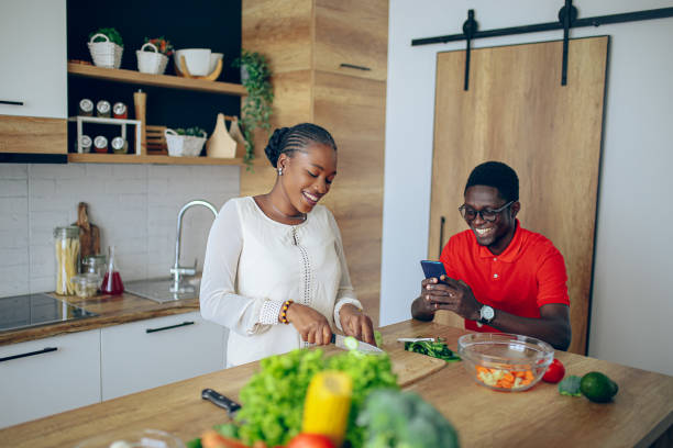 istock Young black couple taking photos with mobile phone while cooking 1559106370