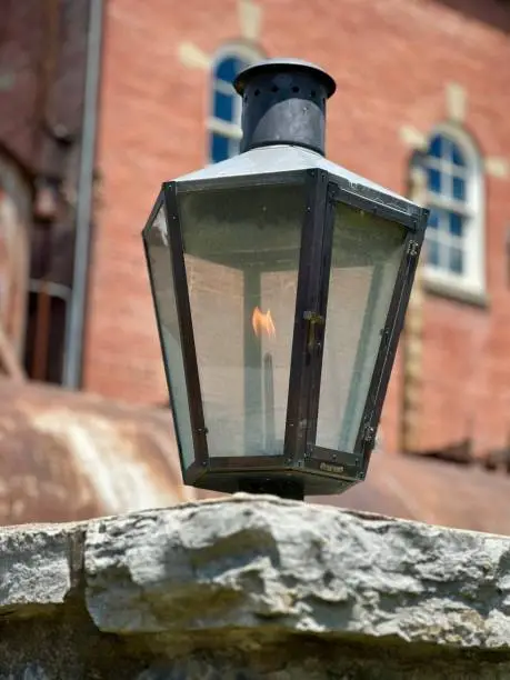 Closeup of a gaslight on a brick wall and brick buildings behind