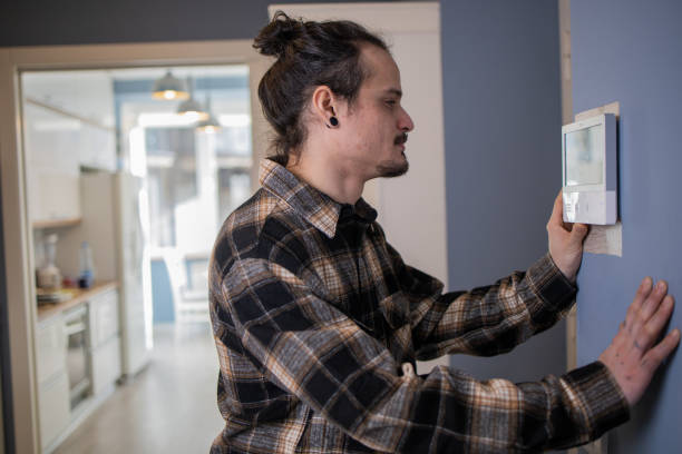 istock Young man adjusts the temperature at home with a device on the wall 1559293595