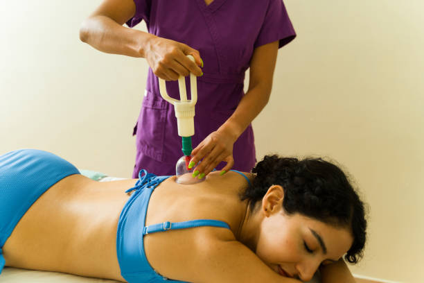 Relaxed beautiful woman relaxing while getting cupping therapy on her back after a body massage at the spa wellness center