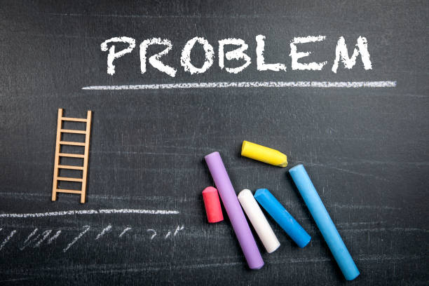 istock PROBLEM. Colored pieces of chalk on a dark chalkboard 1559381968
