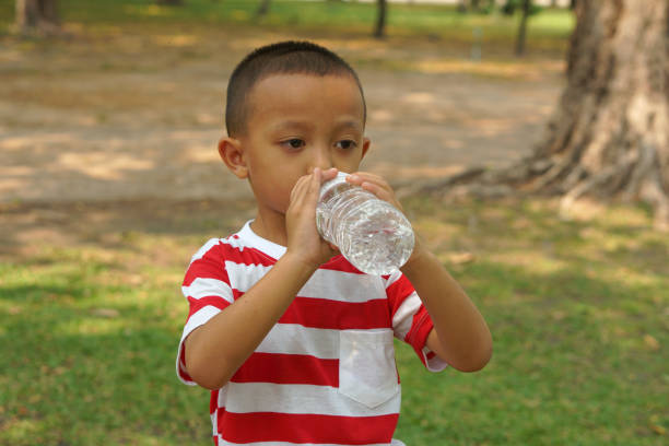 istock Boy playing drinking water in the park 1559392095