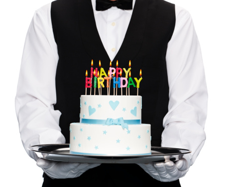 butler holding tray and cake with candles