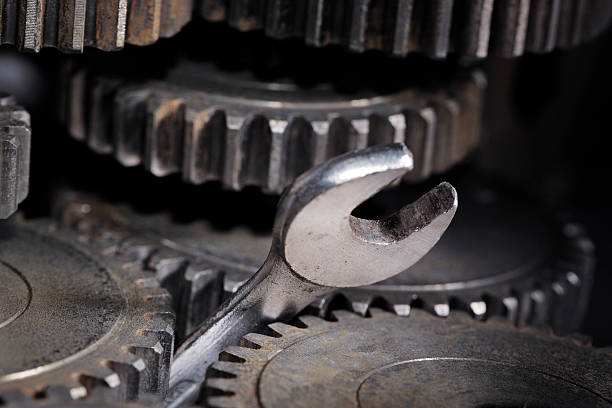A wrench stuck in the middle of some gears stock photo