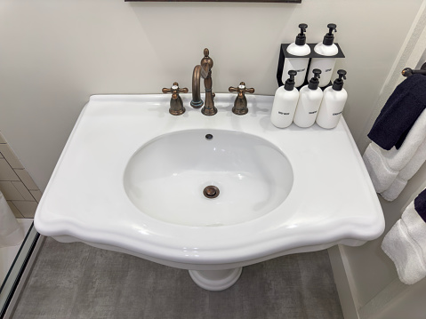 Light gray ceramic acessories for bath - bowl, soap dispenser and electric facial massage machine. Decor for bathroom interior