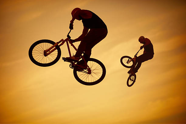 istock Two men performing BMX tricks on their bikes in the air 155950989