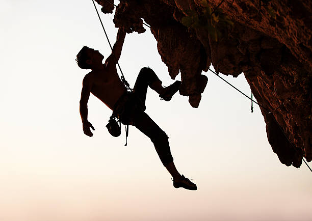 istock Silhouette of a rock climber hanging off cliff with one arm 155951248