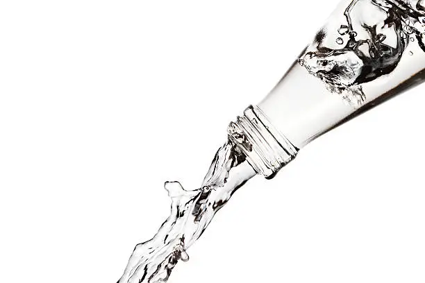 Pouring fresh water from a bottle on a white background