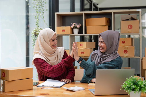 Two woman muslim online business working together, showing a forceful gesture awesome gesture.