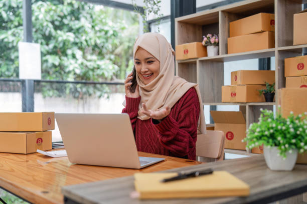 Beautiful Muslim woman selling online at home, business owner, business sme concepts Beautiful Muslim woman selling online at home, business owner, business sme concepts. newspaper seller stock pictures, royalty-free photos & images