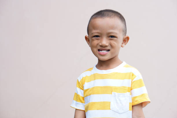 Asian boy smiling happily, cream background