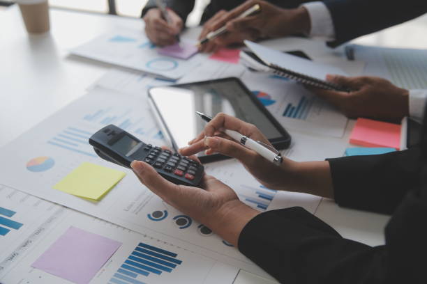 istock Financial analysts analyze business financial reports on a digital tablet planning investment project during a discussion at a meeting of corporate showing the results of their successful teamwork. 1559572584