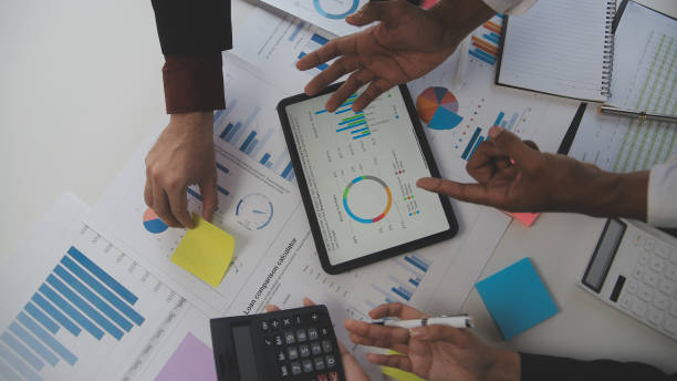 istock Financial analysts analyze business financial reports on a digital tablet planning investment project during a discussion at a meeting of corporate showing the results of their successful teamwork. 1559573667