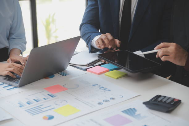 istock Financial analysts analyze business financial reports on a digital tablet planning investment project during a discussion at a meeting of corporate showing the results of their successful teamwork. 1559576330