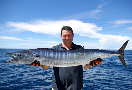 Happy  fisherman holding a beautiful wahoo fish