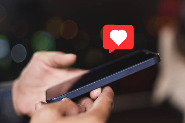 istock Hand holding smartphone with heart sign. 1559702211