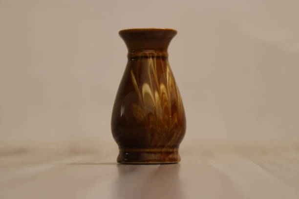 istock A dark brown antique vase with an abstract design in a white background 1559706570
