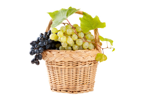 grapes in basket with vine leaves isolated on white