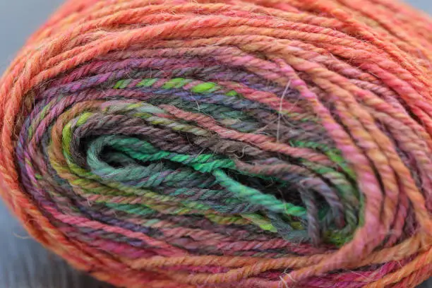 Closeup detail of a colourful skein of organic natural handspun and handdyed merino sheep wool, silk, linnen mix yarn fleece, spun on a traditional spinning wheel