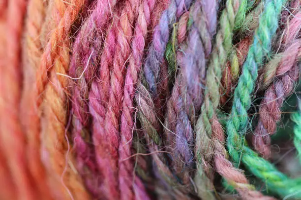 Closeup detail of a colourful skein of organic natural handspun and handdyed merino sheep wool, silk, linnen mix yarn fleece, spun on a traditional spinning wheel