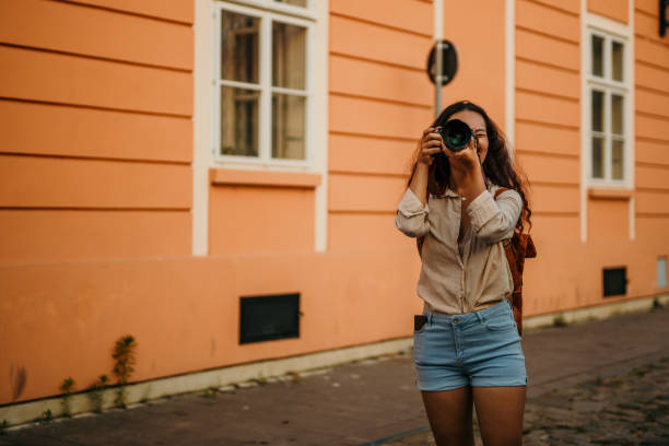 Asian cheerful girl reviewing a picture from her camera on the street.