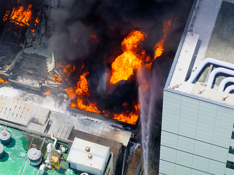 Aerial view of Fire in industrial building. Multi-storey concrete hangar with flames. Factory emergency concept.