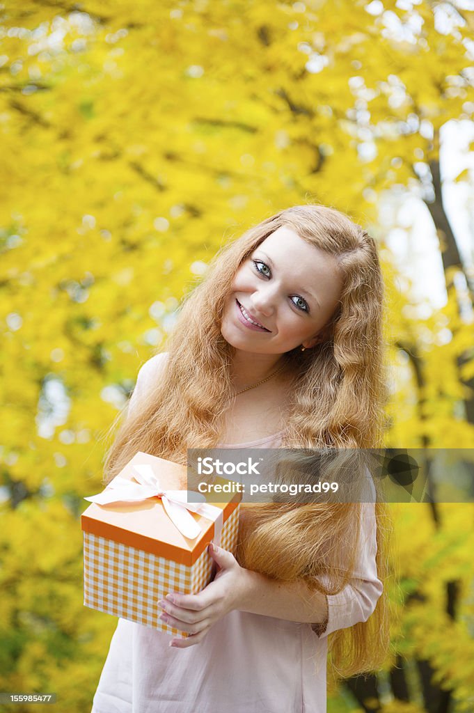 Capelli rossi ragazza con scatola presente in autunno parco - Foto stock royalty-free di Abbigliamento casual