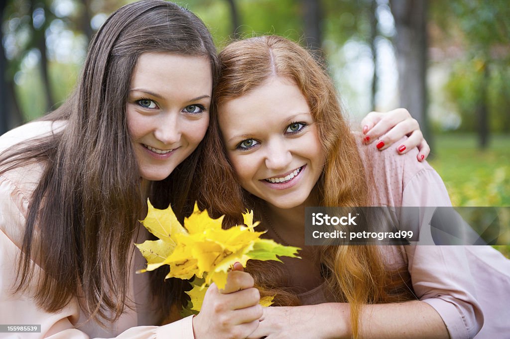 Duas adolescentes com folhas amarelas - Foto de stock de Abraçar royalty-free