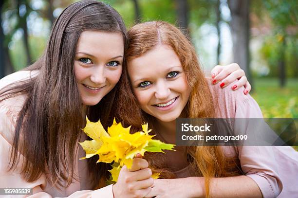 Foto de Duas Adolescentes Com Folhas Amarelas e mais fotos de stock de Abraçar - Abraçar, Adolescente, Adolescentes Meninas