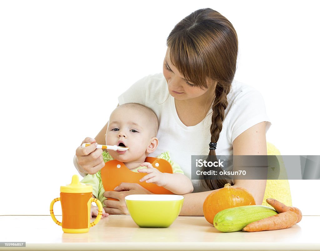 Joven madre cuchara de alimentar a su bebé niño Aislado en blanco - Foto de stock de Bebé libre de derechos