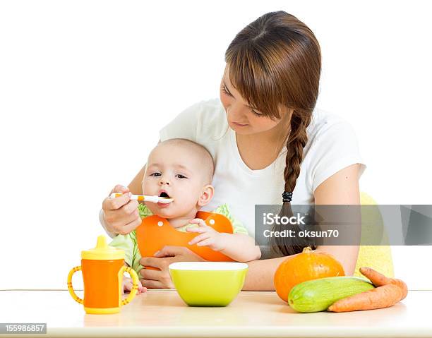 Foto de Jovem Mãe Alimentando Seu Bebê Menino Uma Colher Isolado No Branco e mais fotos de stock de Bebê