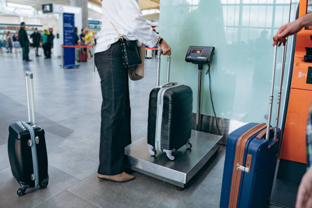 mujer elegante poniendo maleta en pesas en el equipaje del aeropuerto - instrument of weight fotografías e imágenes de stock