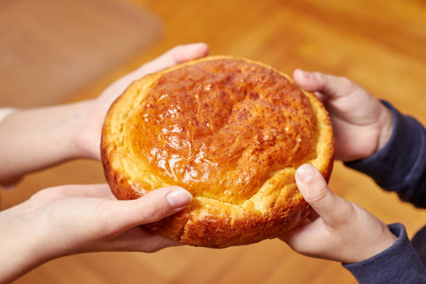 istock Two pairs of hands holding ruddy freshly baked bread. 1559929000