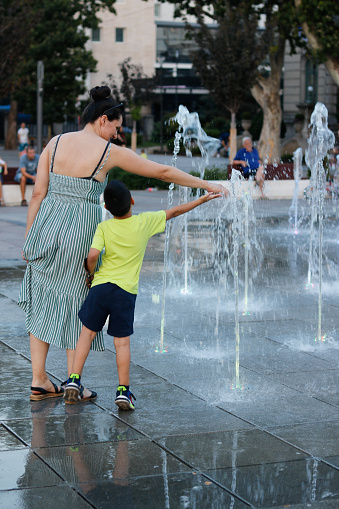 Mother and child cool off at a fountain in the city