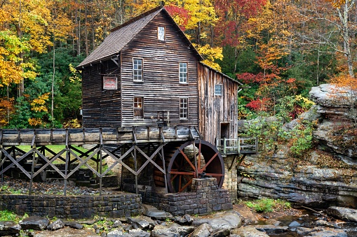 Fayette, United States – October 19, 2022: A wooden water mill situated on the banks of a tranquil river in Babcock State Park, West Virginia.