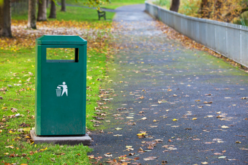 Green Metal Waste Container In The Park on the side of walkway