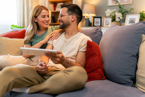 Husband showing something on the digital tablet to his wife at home