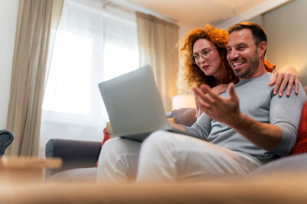 istock Couple using a laptop while sitting on the sofa at home. 1559981506