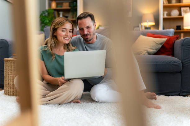 Couple planning vacation trip while sitting on floor and using laptop.
