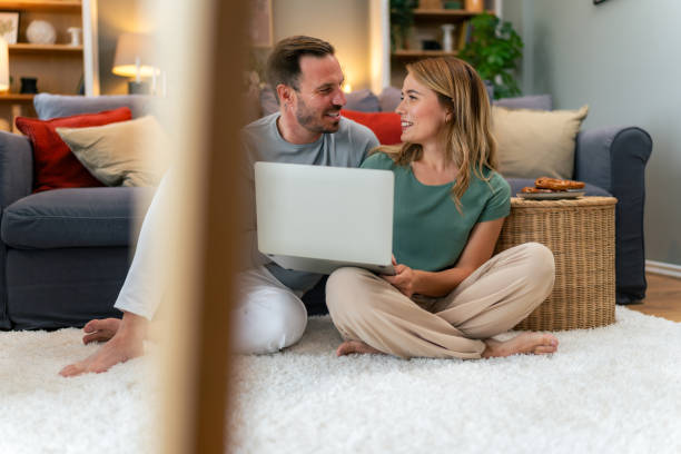 istock Happy Couple Relaxing With Laptop On Floor At Home 1559983151