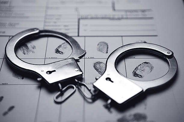 Handcuffs And Fingerprints Handcuffs on top of a fingerprint form. arrest photos stock pictures, royalty-free photos & images