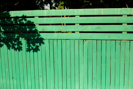 Wooden fence. Green board. Fencing in rural areas. Details of construction.