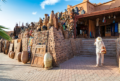 Ouarzazate, Morocco - May 11, 2023: Tourist in front of the shops of antiques in Ouarzazate. Morocco, Africa.