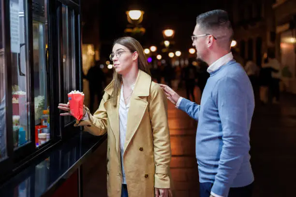Boyfriend and Girlfriend Delight in a Street Snack on their Evening Stroll