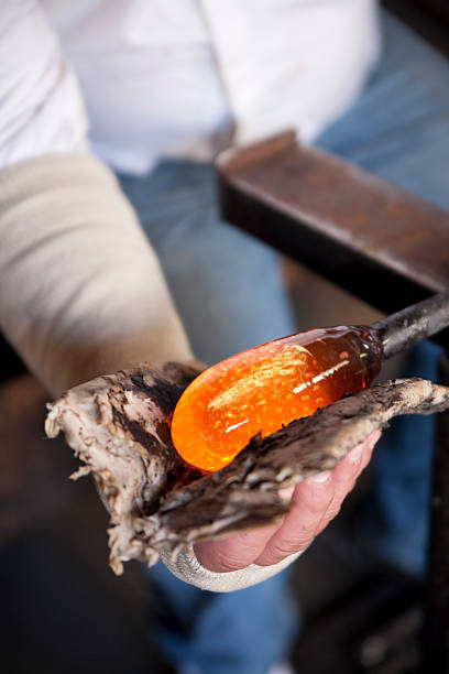 Glassblower shaping molten glass stock photo