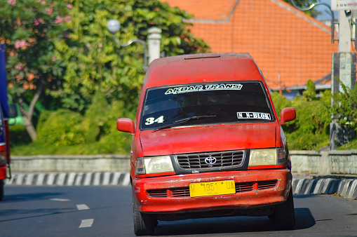 Public transportation or angkot are red on Indonesian highways. a Toyota Kijang car that has changed its function to become an angkot that goes from Surabaya to Gresik, Indonesia, 23 June 2023.