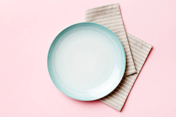 istock Top view on colored background empty round blue plate on tablecloth for food. Empty dish on napkin with space for your design 1560042249