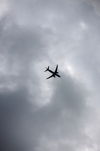 Commercial aeroplane flying through an overcast sky.