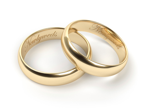 Gold wedding rings engraved with the text Newlyweds