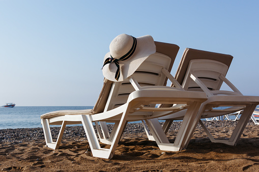 Vacations and accessories concept. Two sun loungers on a beach. Sand and sea background. Bottom rear view